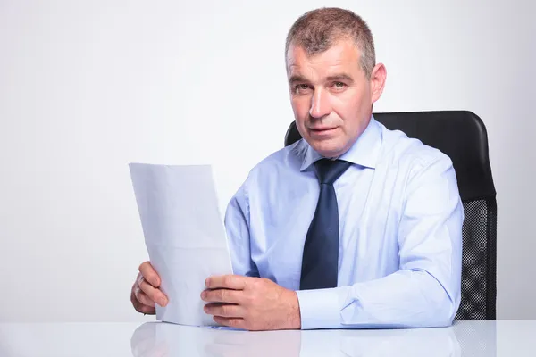 Old business man sits at desk with documents