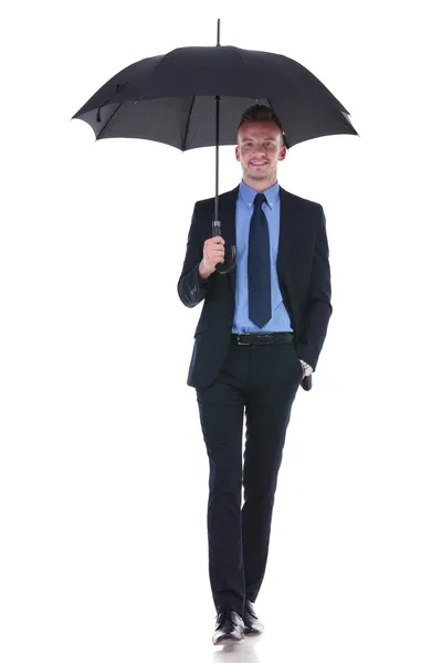 Business man walks with umbrella