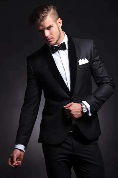 Business man posing with hand on tuxedo jacket