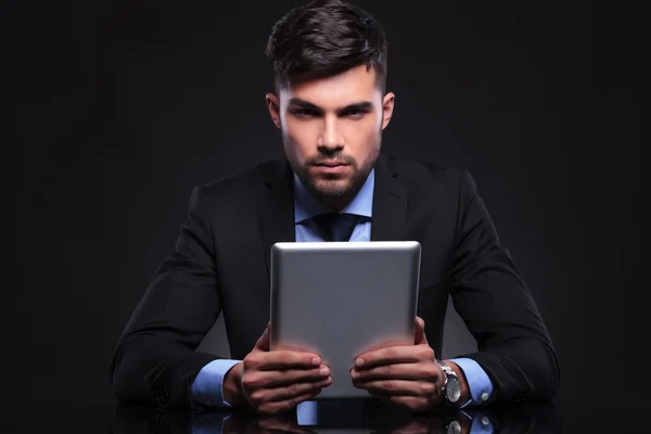 Young business man holds tablet and looks at you