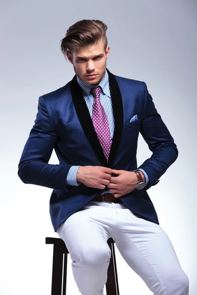 Seated young business man taking his jacket off