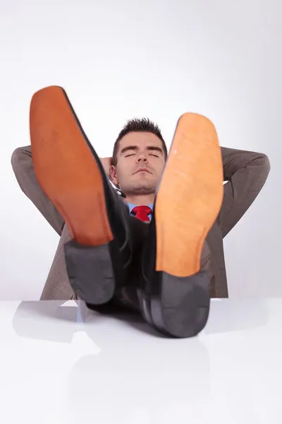 Young business man sleeps at office with feet on desk
