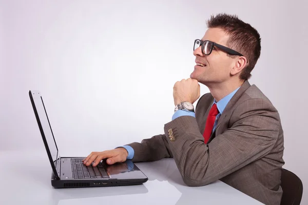 Side of young business man with laptop, looking up with hand on