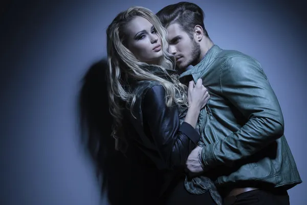 Woman in leather jacket is pulling her lover closer