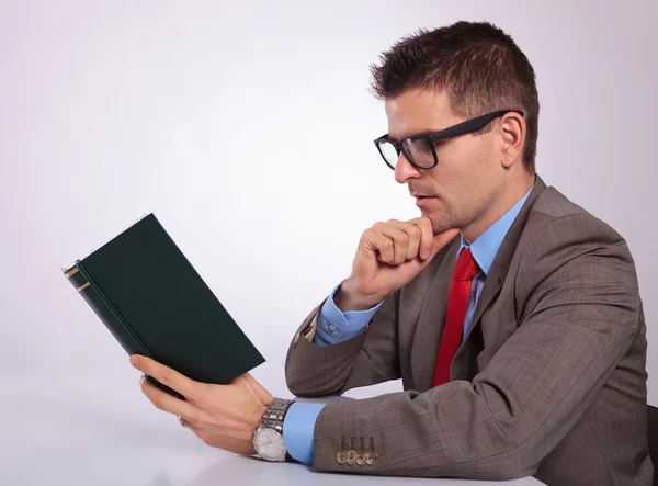 Side of young business man reading a book pensively