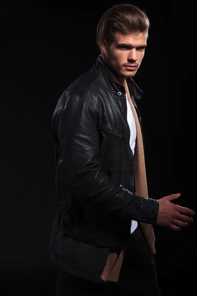 Side view of a young man in leather jacket is walking