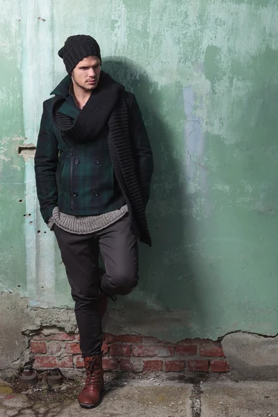 Young fashion man leans on old wall