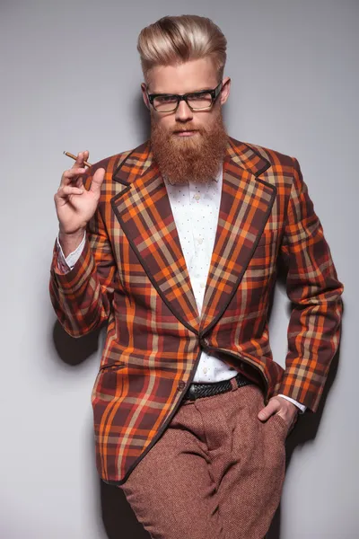 Serious fashion man with beard and nice hairstyle smoking