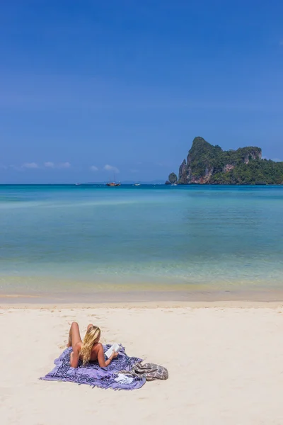 Young blonde woman reading a book on Phi Phi island
