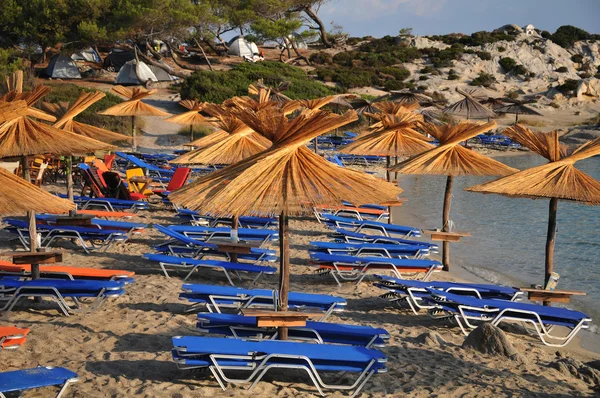 Greek beaches of white sand and stone, with cafes and beach umbrellas of pa