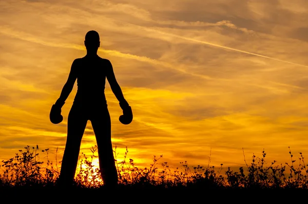 那个女孩在拳击手套日落时的剪影 - 图库照片p