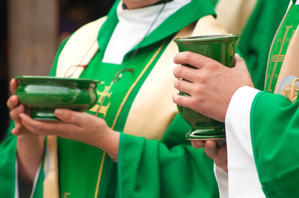 Christian priests holding bowls with wafer and wine during sacrament.