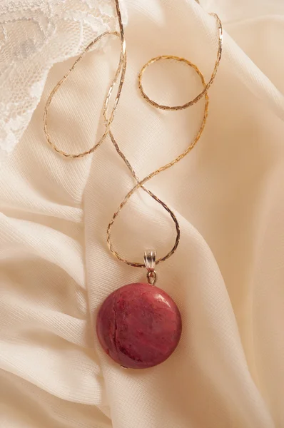 Silver necklace with semiprecious stone lying on white silk