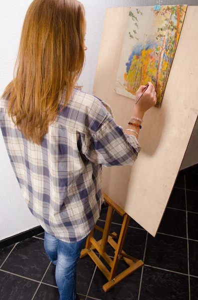 Young female painter painting landscape in her art studio
