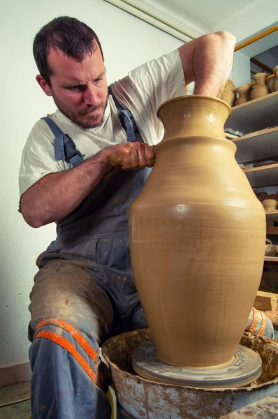 Craftsman making huge vase on pottery wheel