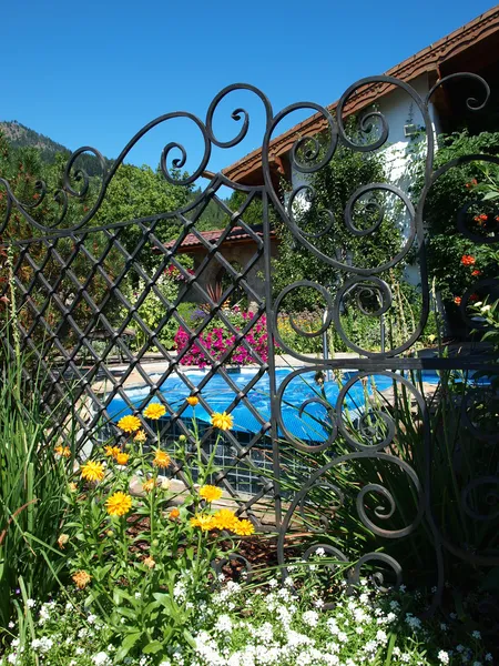 Looking Through a Metal Fence to a Pool and Garden