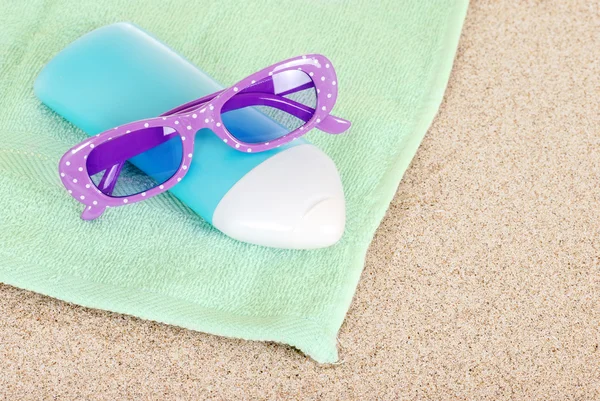 Suntan lotion sun glasses and beach towel