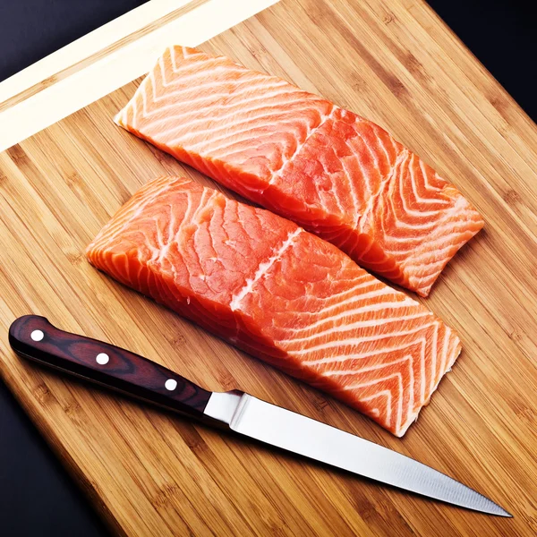 Salmon fillet with knife on wood board