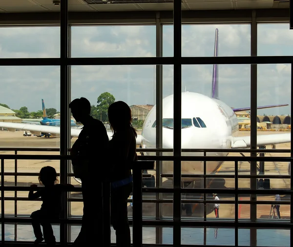 A family at an airport terminal with aeroplane in the background
