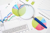 Magnifying glass atop business graphs
