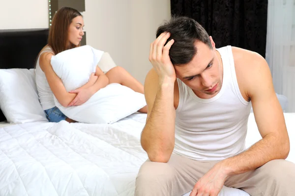 Upset man having problem sitting on the bed with his girlfriend