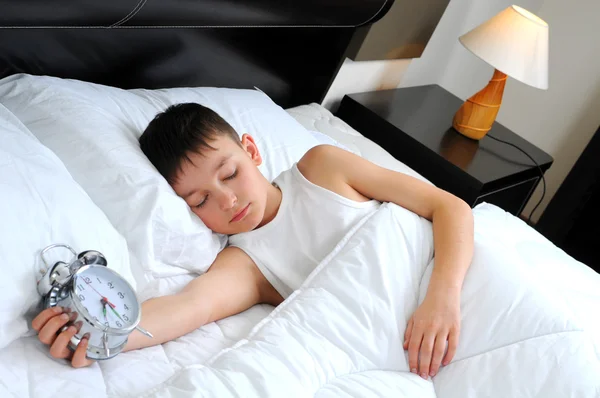 Sleeping boy with alarm clock in front