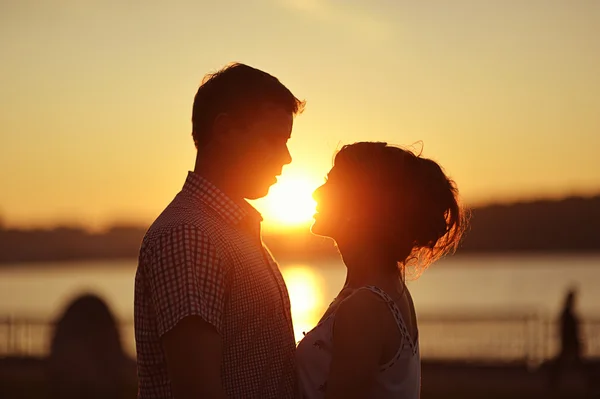 Couple in love back light silhouette at lake orange sunset