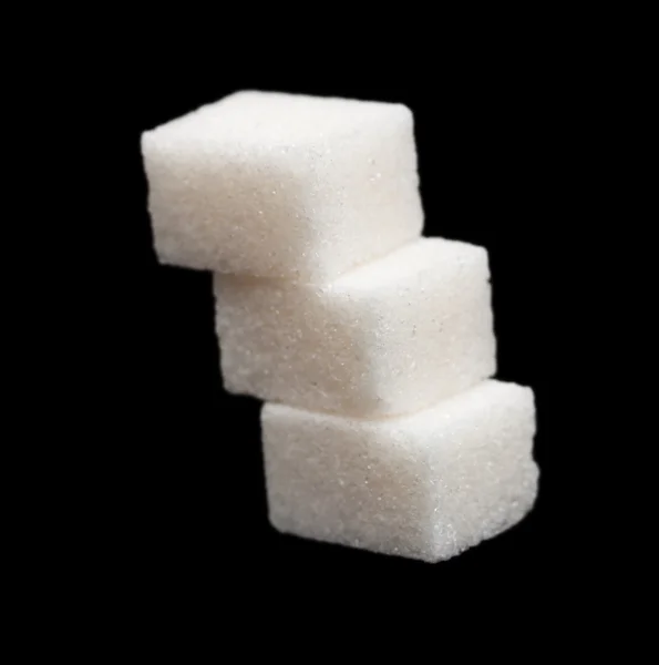Three lumps of sugar on a black background
