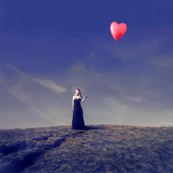 Elegant Blonde Girl Letting Go Off a Heart Shaped Balloon