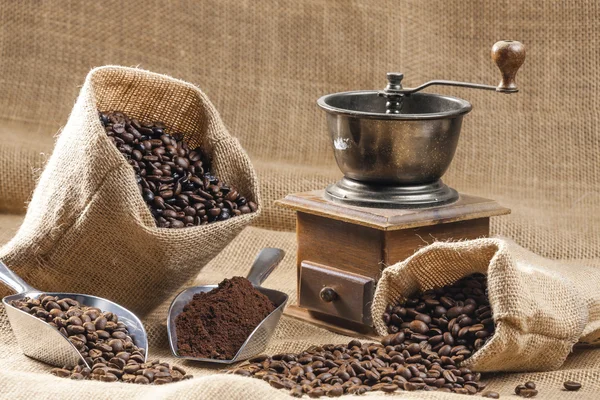 Still life of coffee beans in jute bags with coffee grinder