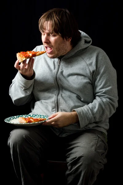 Overweight man eating a pizza.