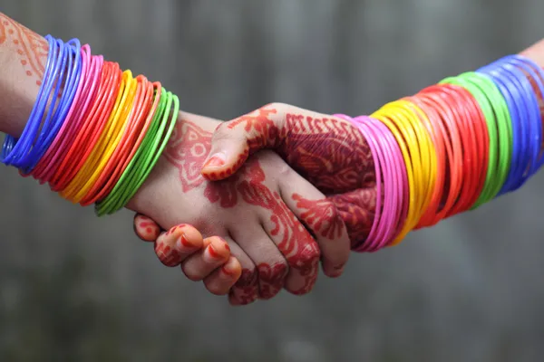 Shaking hands decorated with colorful bracelets