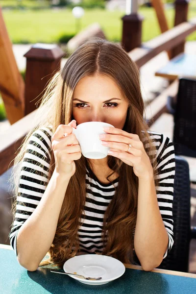 Young woman drinking coffee in a cafe outdoors