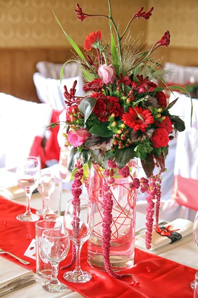 Vase of red flowers on a red tablecloth