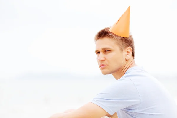 Guy in party hat on beach closeup