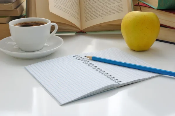 Notebook with a pencil on a table with a cup of coffee and an ap