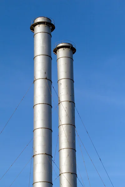 Industrial smoke pipes over blue sky vertical view