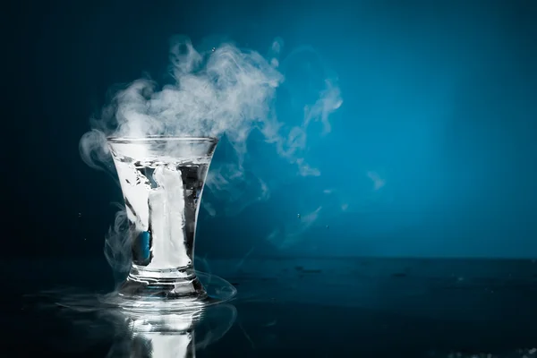 Shot glass of vodka with ice vapor