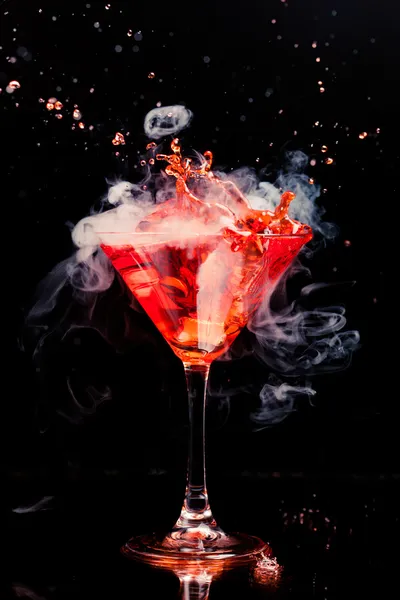 Red cocktail with splash and ice vapor