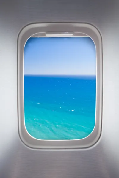 Side window of airplane with sea view
