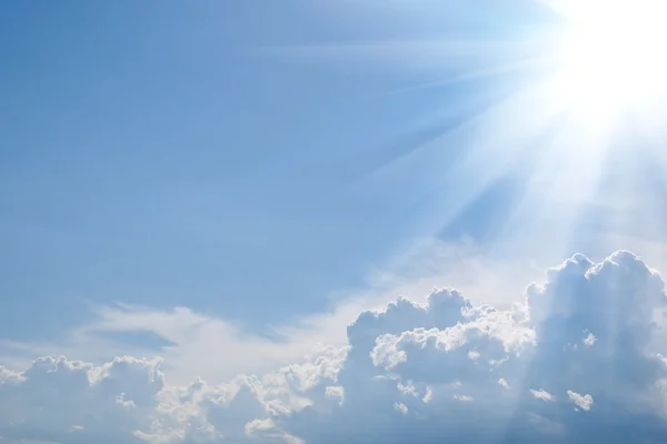 Blue background with sunshine, dense clouds and copy-space