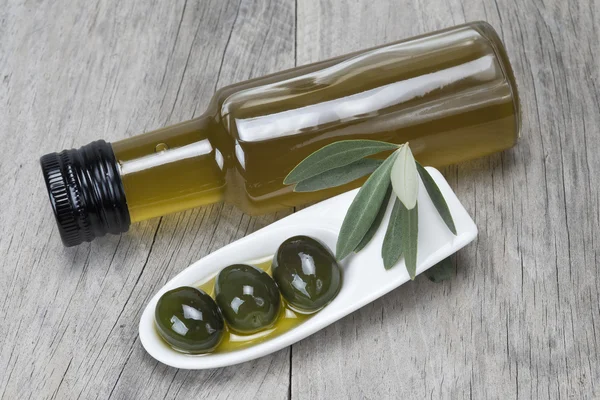 Olive oil and olives on a wooden surface
