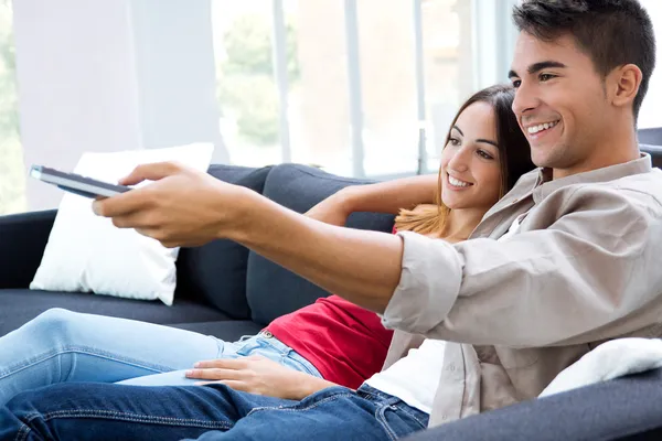 Portrait of happy couple sitting on sofa and watching television together