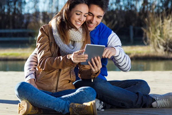 Outdoor portrait of young couple with digital tablet