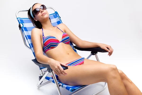 Beautiful young woman with bikini sitting on a beach chair