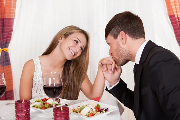 Man kissing a woman\'s hand at a romantic dinner