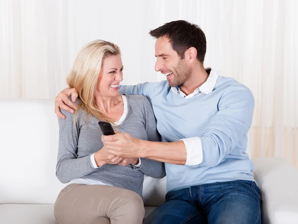 Young couple fighting for TV remote