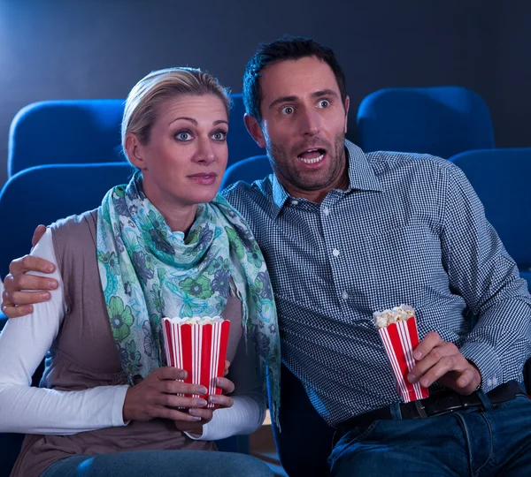 Couple watching a movie reacting in horror