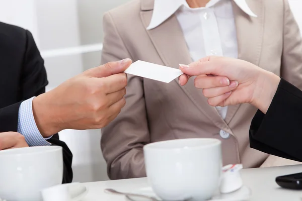 Businesspeople exchanging cards over coffee