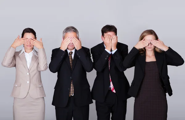 Four businesspeople holding their eyes shut
